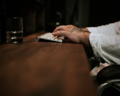 A glass of water next to a keyboard in an office environment