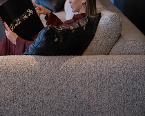 A person resting on a comfortable sofa reading a book